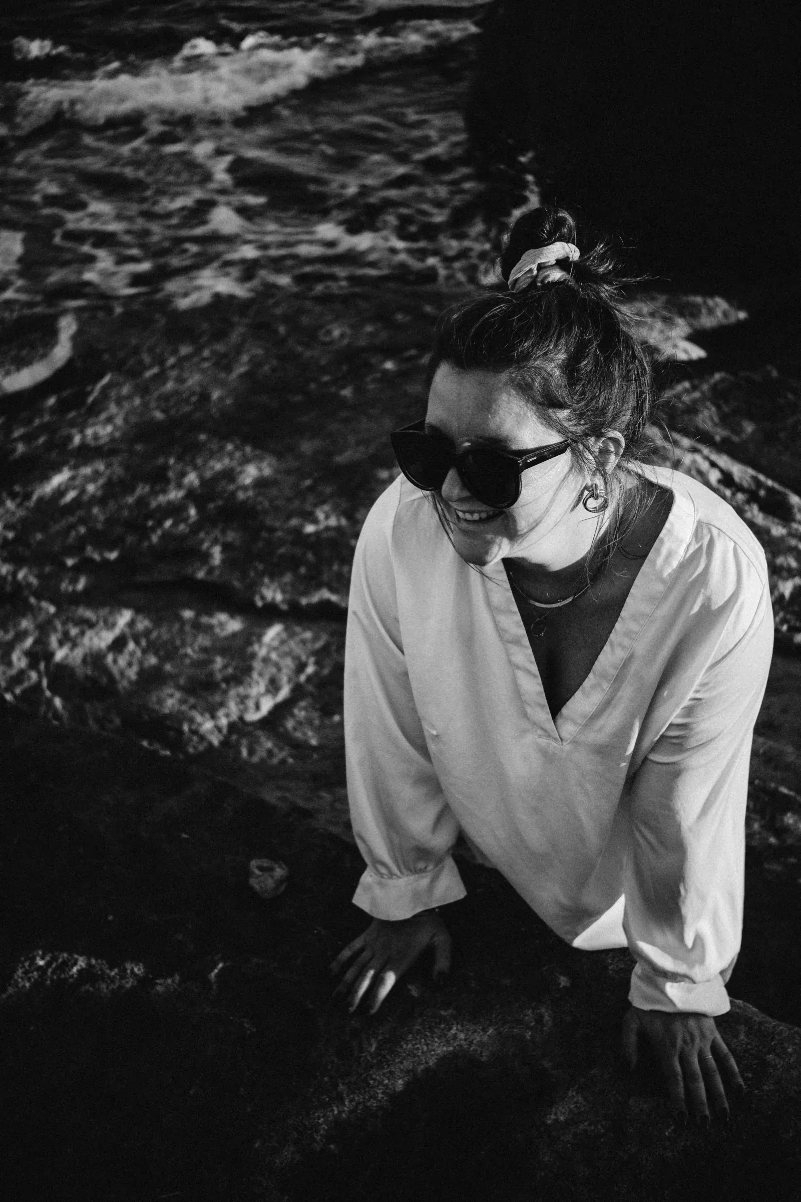 Svenja, Zweitfotografin, lachend am Wasser sitzend — Schwarz-Weiß-Portrait